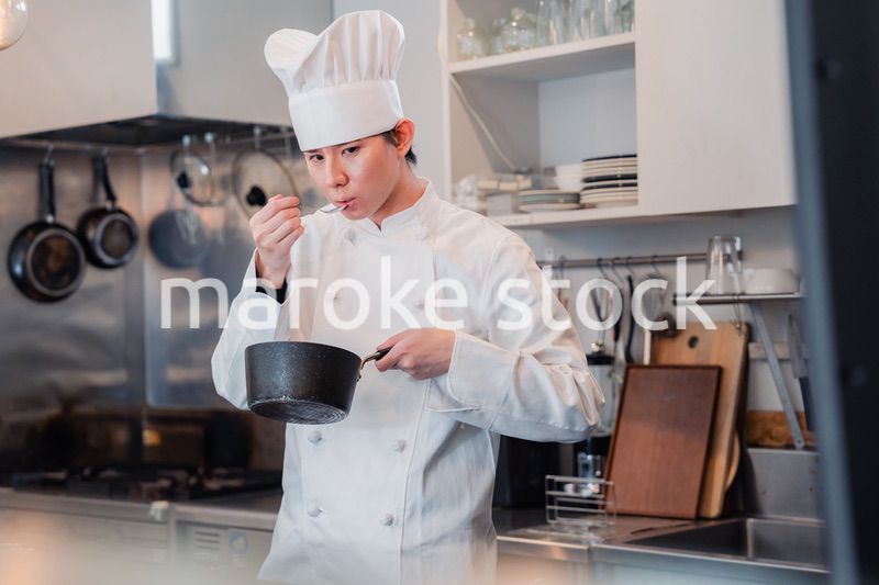 厨房で味見をする男性シェフ