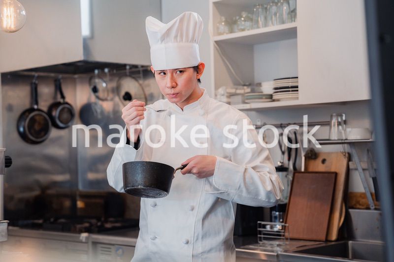 厨房で味見をする男性シェフ