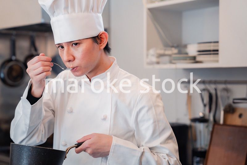 厨房で味見をする男性シェフ