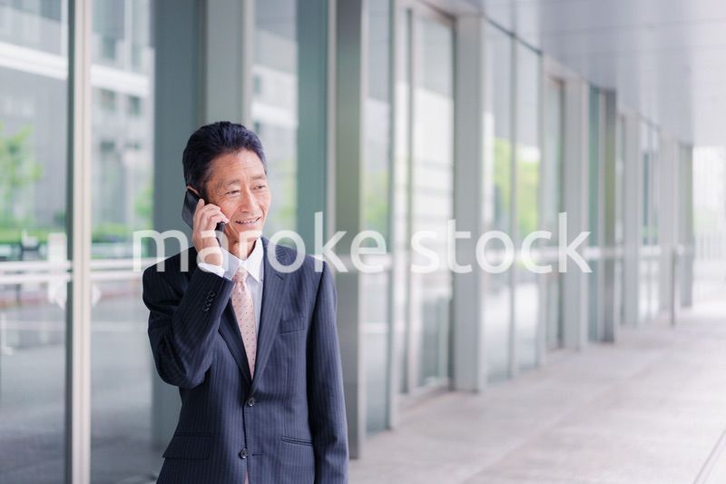 オフィス街で電話をするサラリーマンの男性