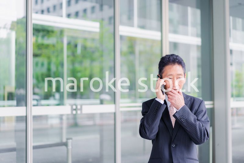 オフィス街で電話をするサラリーマンの男性
