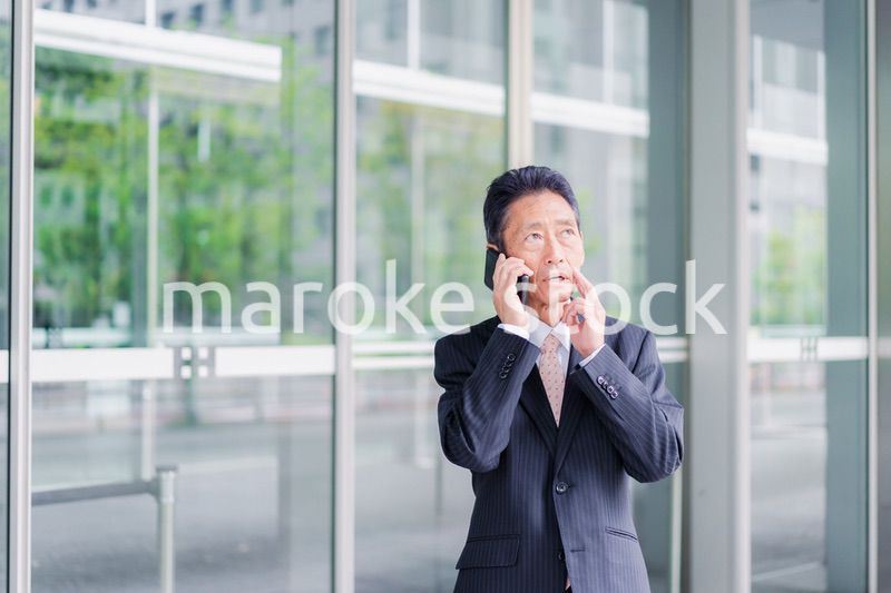 オフィス街で電話をするサラリーマンの男性