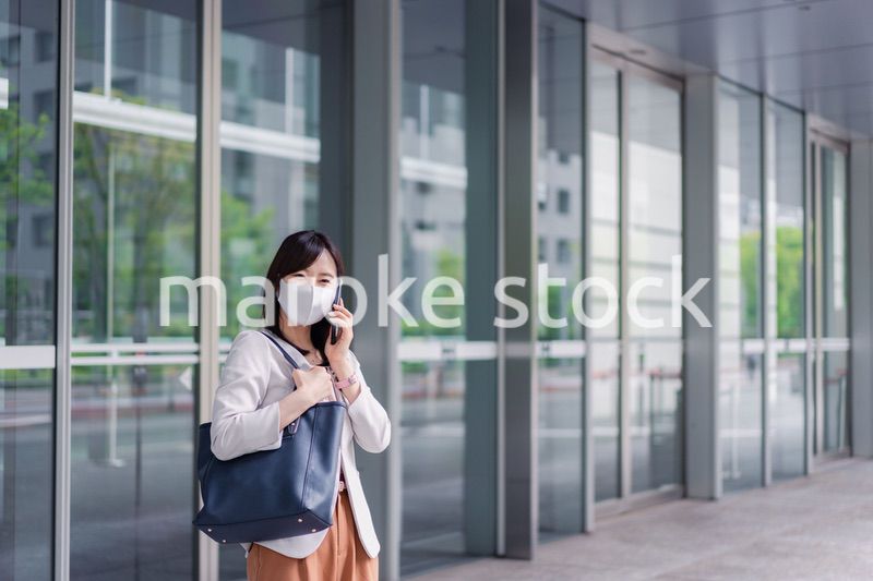 マスクをしてスマホを使う若い女性