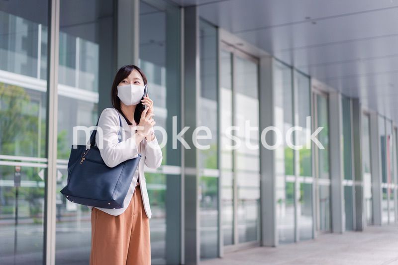 マスクをしてスマホを使う若い女性