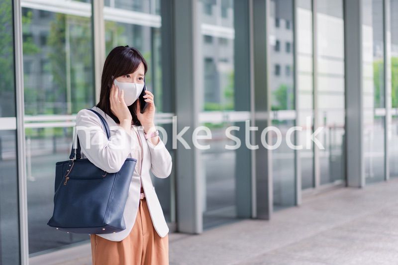 マスクをしてスマホを使う若い女性