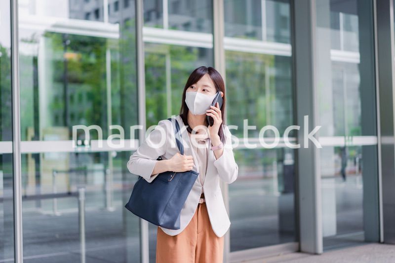 マスクをしてスマホを使う若い女性