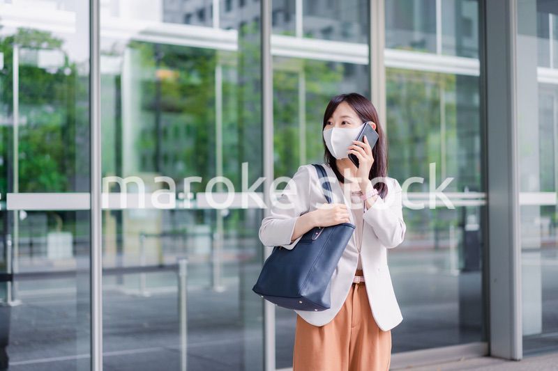 マスクをしてスマホを使う若い女性