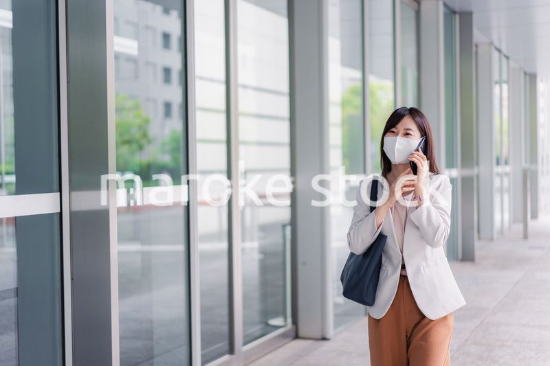 マスクをしてスマホを使う若い女性
