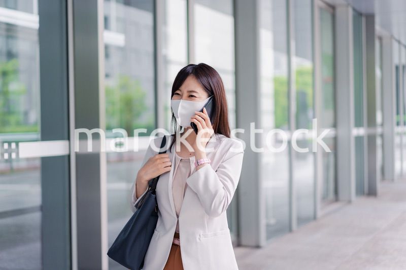 マスクをしてスマホを使う若い女性