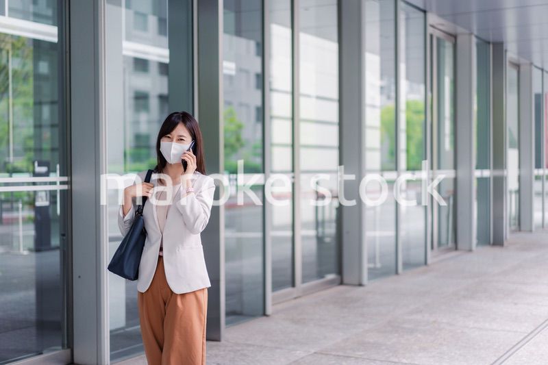 マスクをしてスマホを使う若い女性