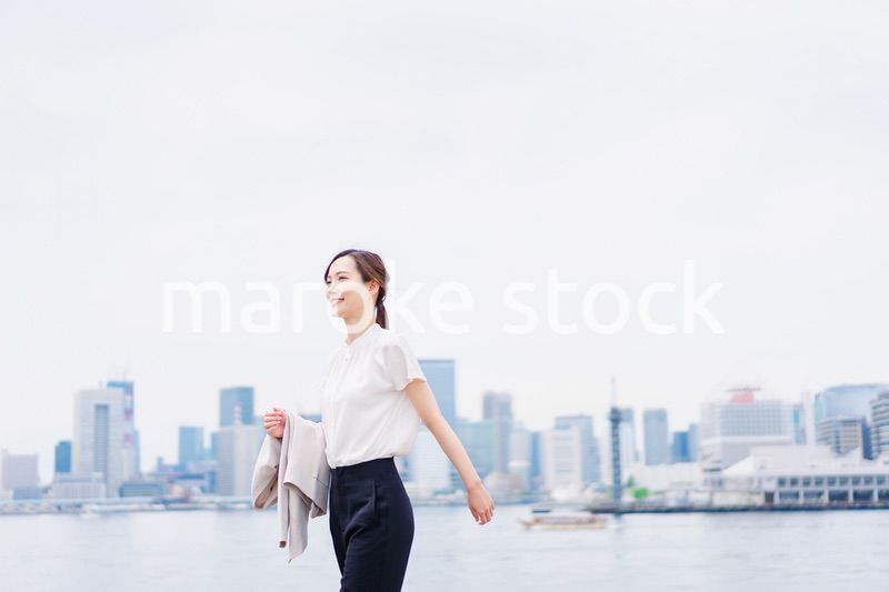 ジャケットを脱いで外を歩くビジネスウーマン