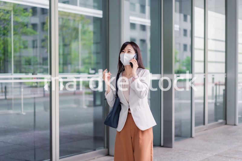 マスクをしてスマホを使う若い女性