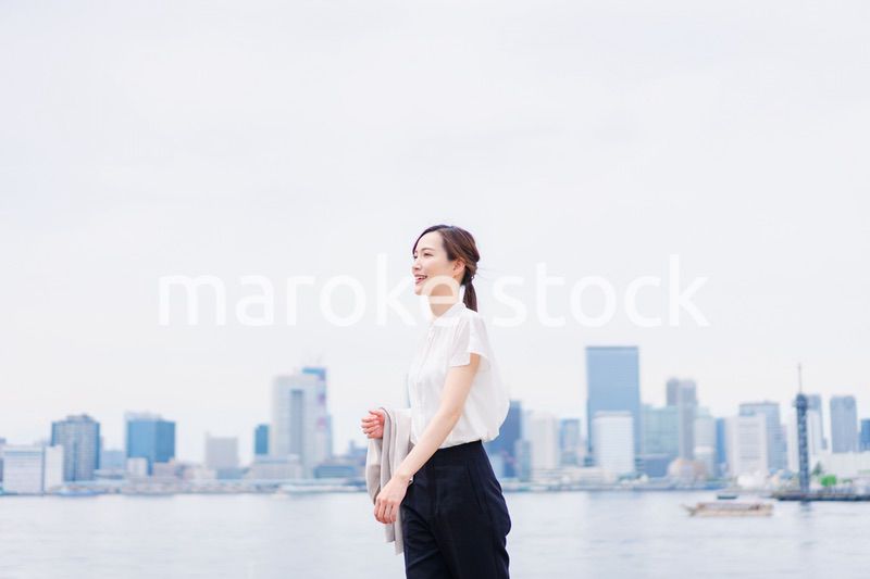 ジャケットを脱いで外を歩くビジネスウーマン