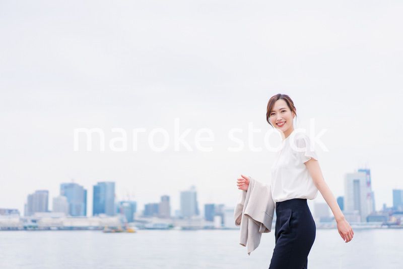 ジャケットを脱いで外を歩くビジネスウーマン