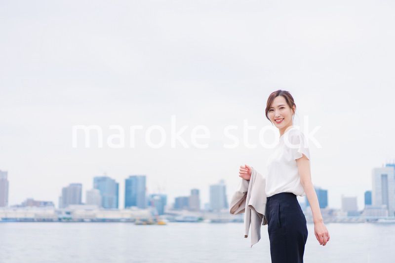 ジャケットを脱いで外を歩くビジネスウーマン