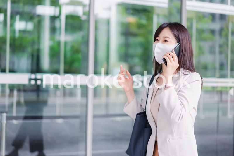 マスクをしてスマホを使う若い女性