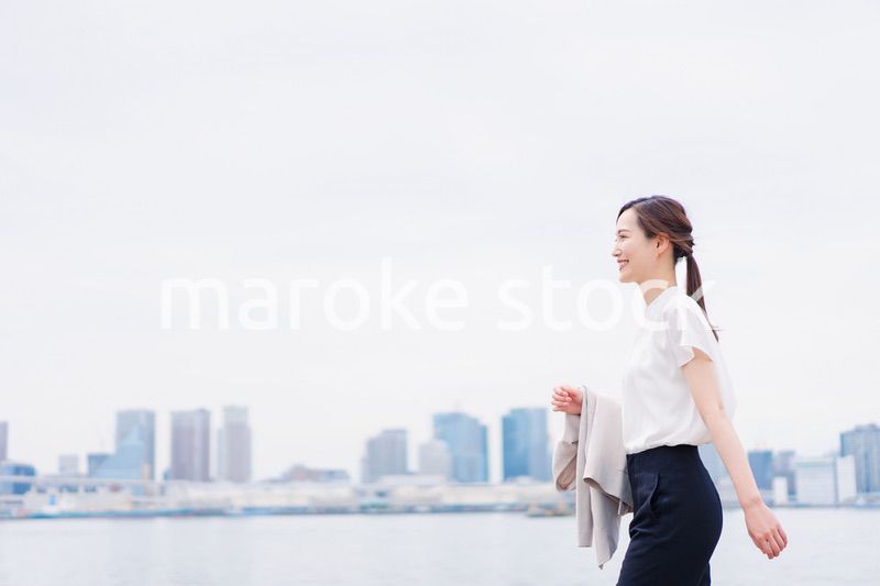 ジャケットを脱いで外を歩くビジネスウーマン