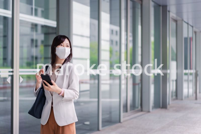 マスクをしてスマホを使う若い女性