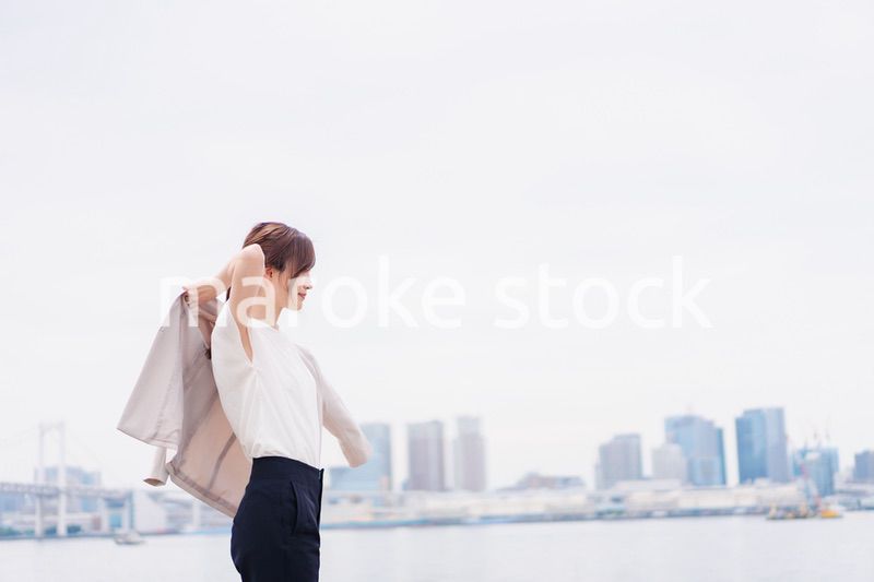 都会でジャケットを脱ぐビジネスウーマン