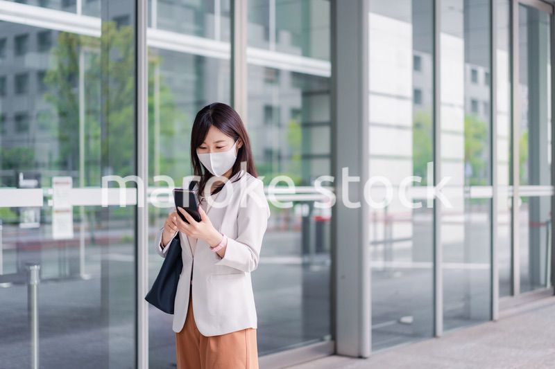 マスクをしてスマホを使う若い女性
