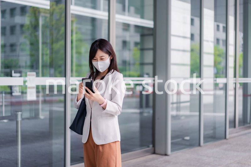 マスクをしてスマホを使う若い女性