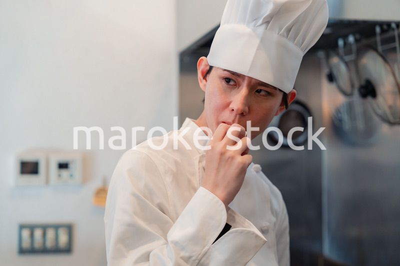 厨房で味見をする男性のシェフ