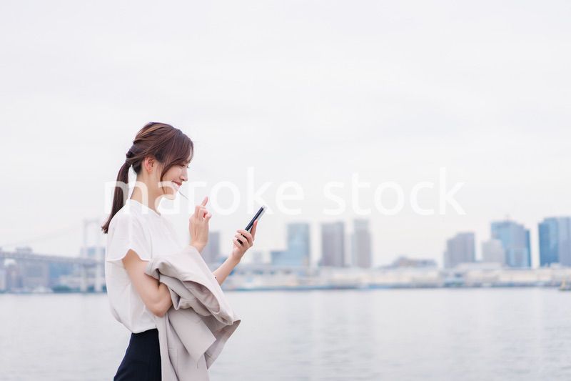 屋外でメッセージを打つ若い女性