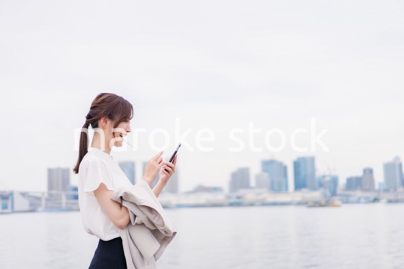 屋外でメッセージを打つ若い女性