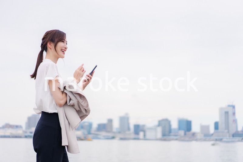 屋外でメッセージを打つ若い女性