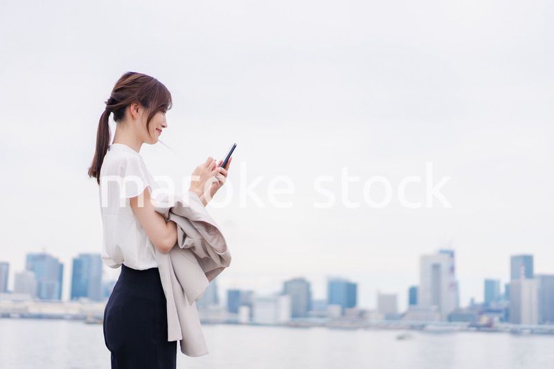 屋外でメッセージを打つ若い女性