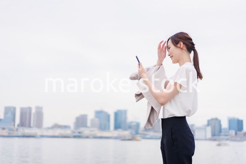 屋外でメッセージを打つ若い女性