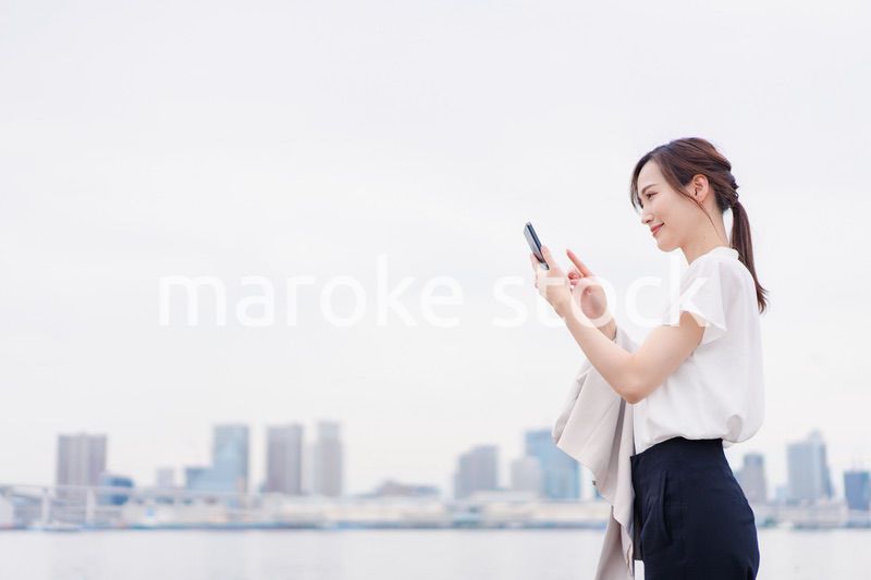 屋外でメッセージを打つ若い女性