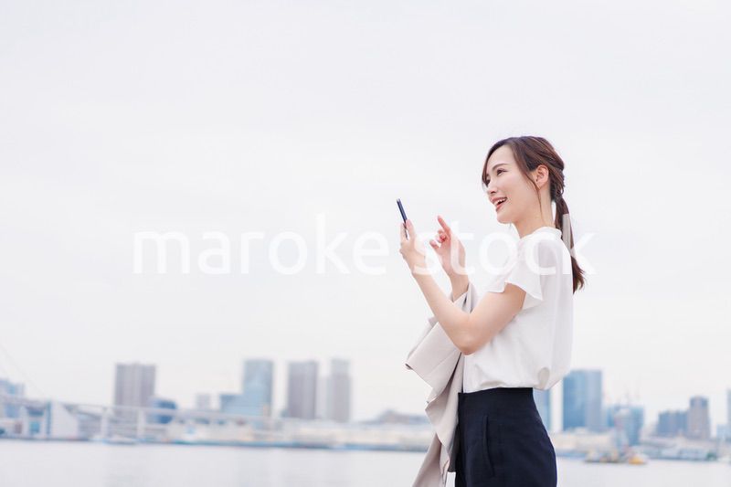 屋外でメッセージを打つ若い女性