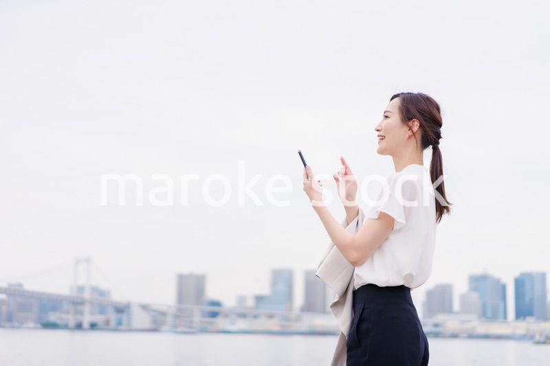 屋外でメッセージを打つ若い女性