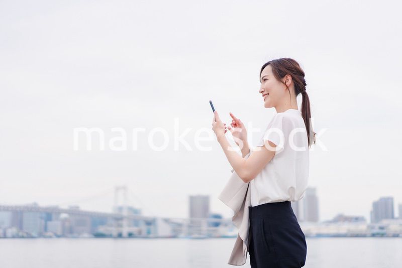 屋外でメッセージを打つ若い女性