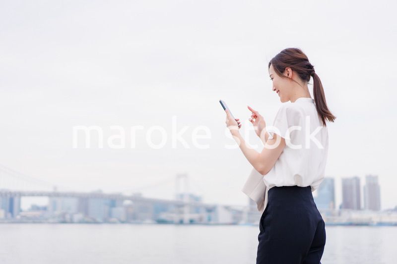 屋外でメッセージを打つ若い女性