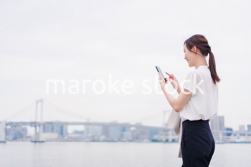 屋外でメッセージを打つ若い女性