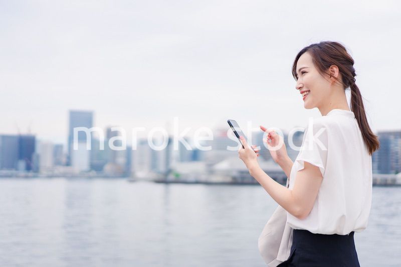 屋外でメッセージを打つ若い女性