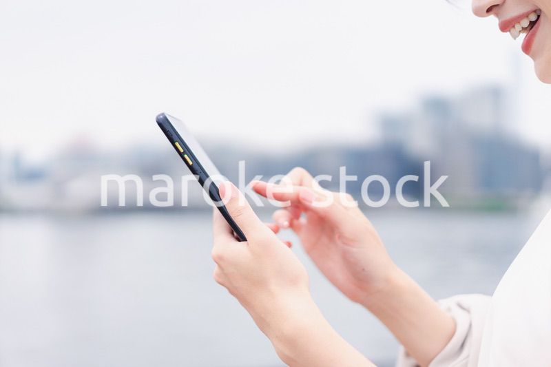 屋外でメッセージを打つ若い女性