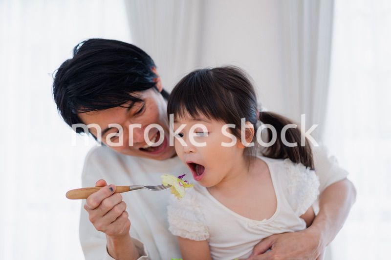 パパと一緒にご飯を食べる小さな女の子