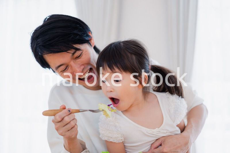 パパと一緒にご飯を食べる小さな女の子