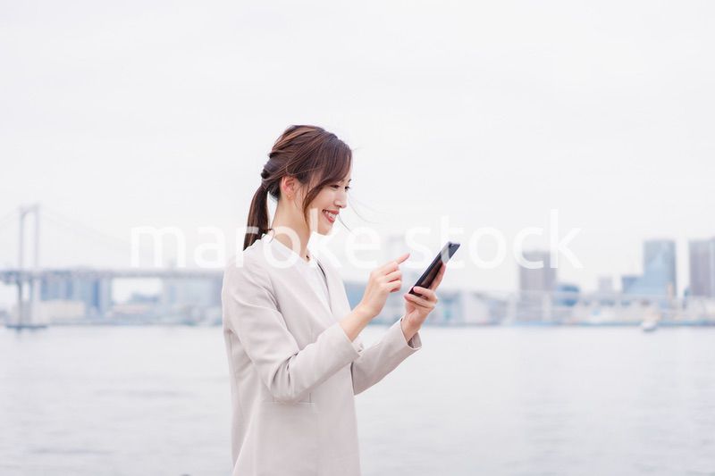 屋外でメッセージを打つ若い女性