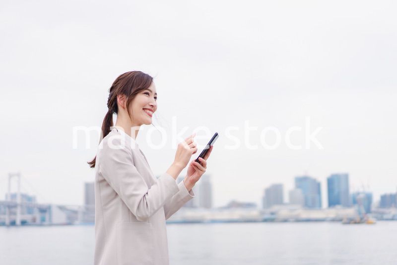 屋外でメッセージを打つ若い女性