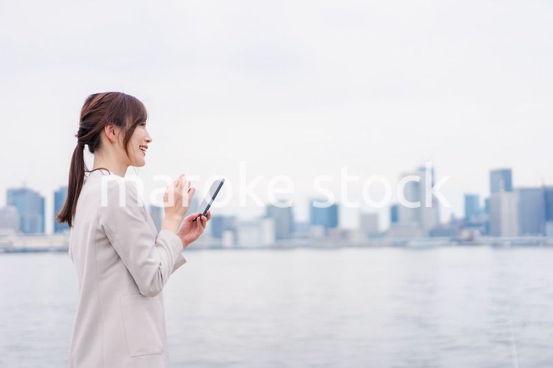 屋外でメッセージを打つ若い女性