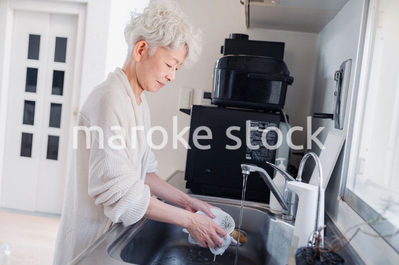 キッチンで洗い物をするシニア女性