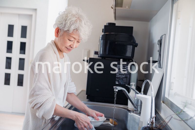 キッチンで洗い物をするシニア女性