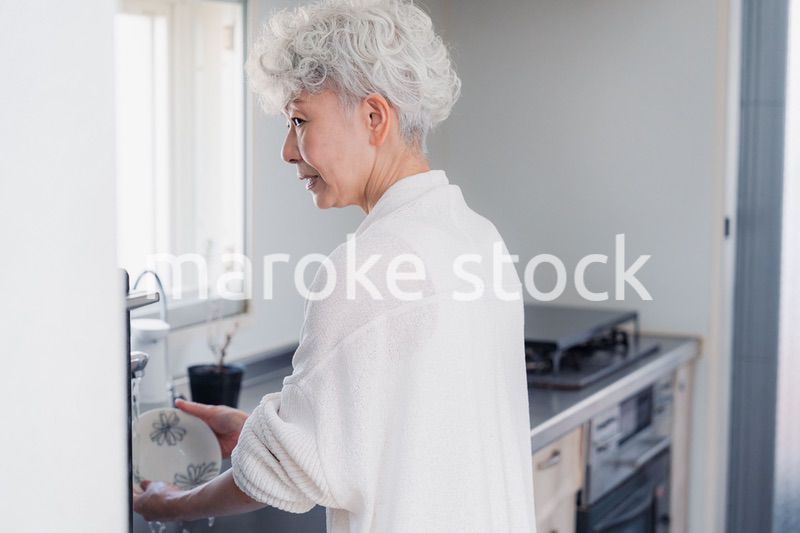 キッチンで洗い物をするシニア女性