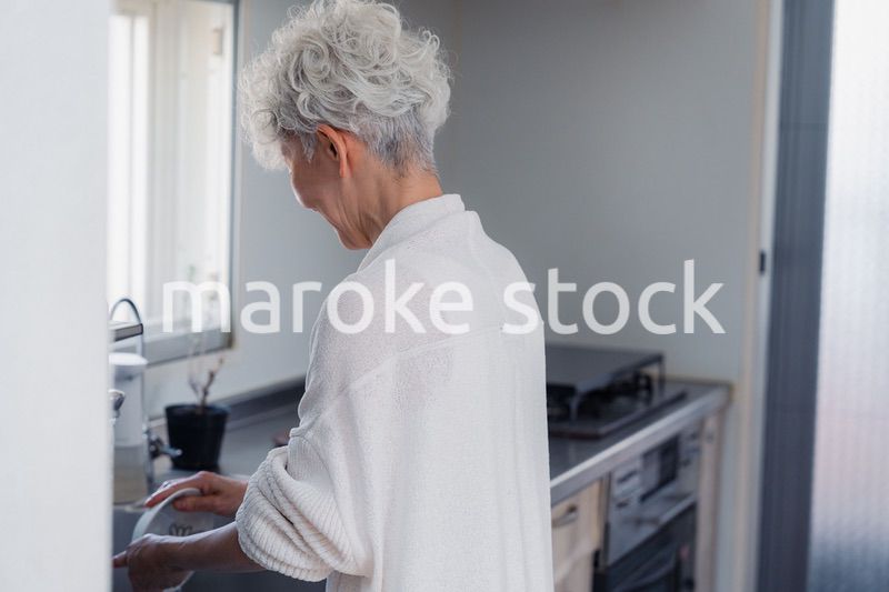 キッチンで洗い物をするシニア女性