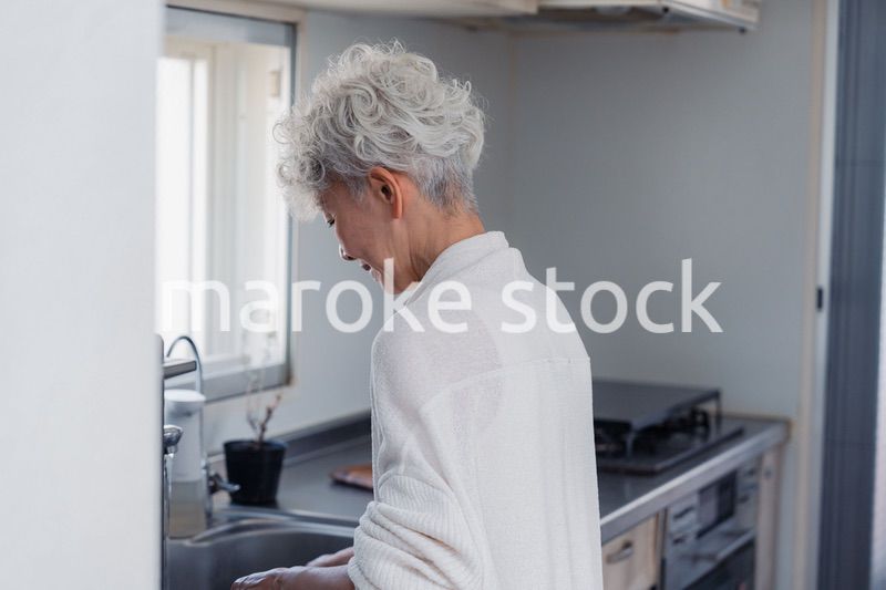キッチンで洗い物をするシニア女性
