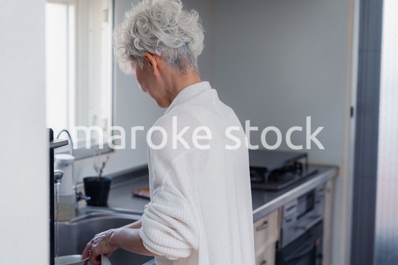 キッチンで洗い物をするシニア女性